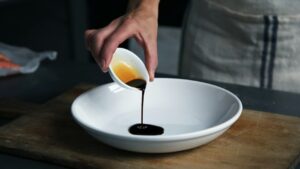 Mörk sås hälls från en liten skål i en vit serveringsskål